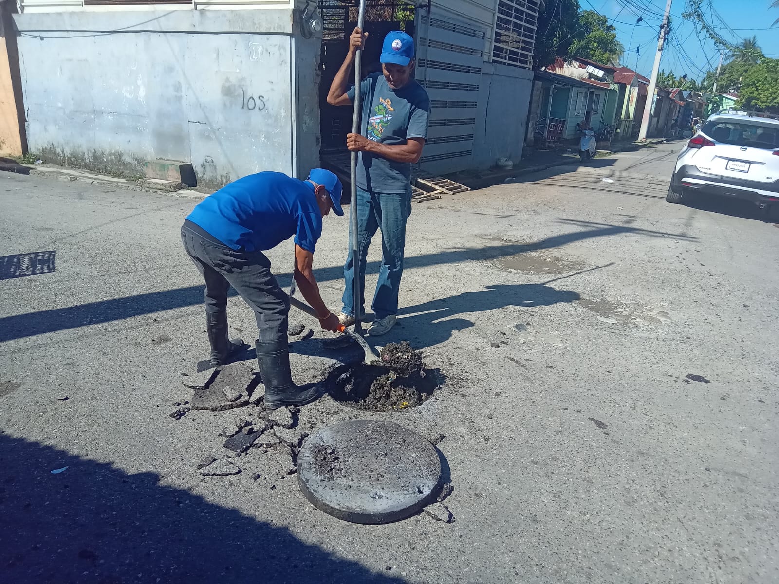 Dos empleados de la brigada de agua residual de CORAAPPLATA destapan un filtrante
